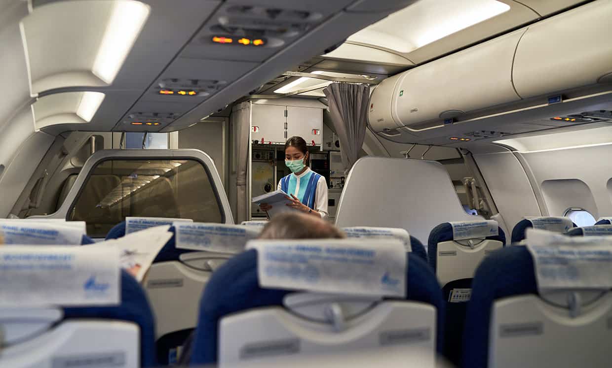 Aasialainen lentoemäntä lukee turva-ohjeita tyhjässä lentokoneessa