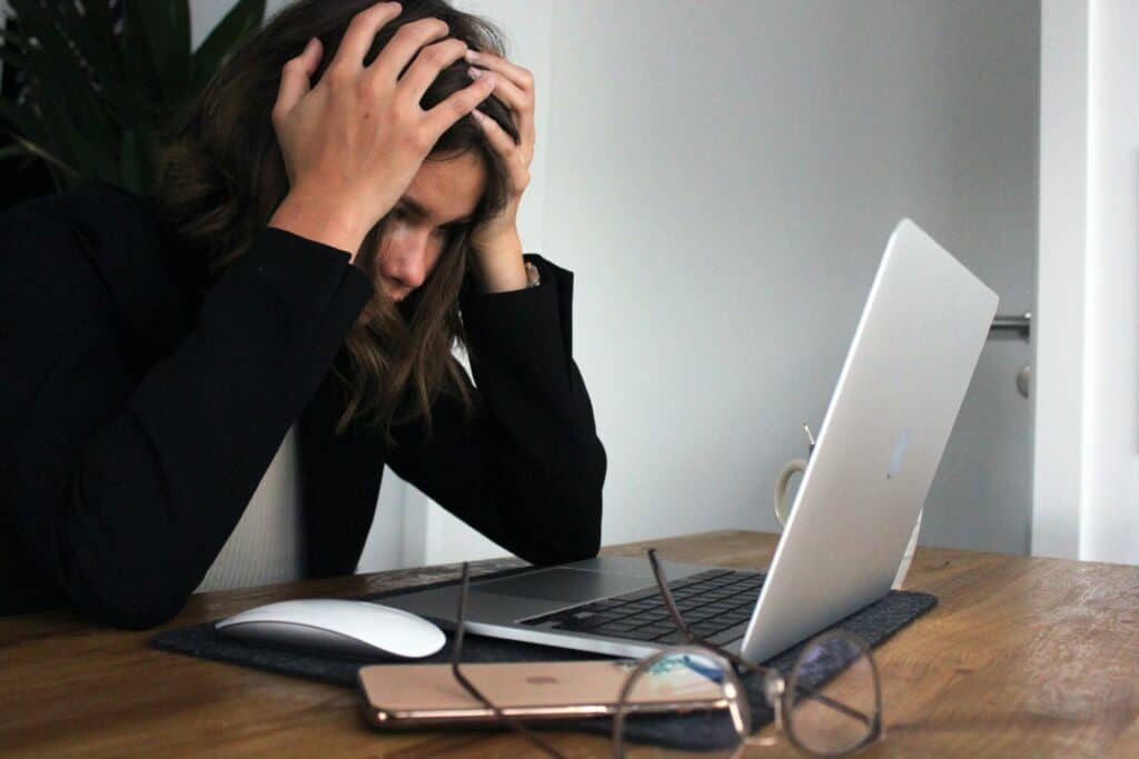 Stressaantunut nainen kannettavan tietokoneen äärellä.