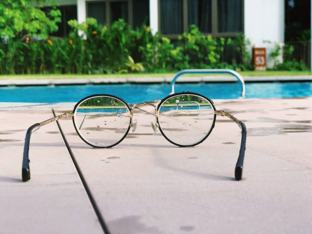Kuva kastuneista silmälaseista uima-altaan reunalla.
