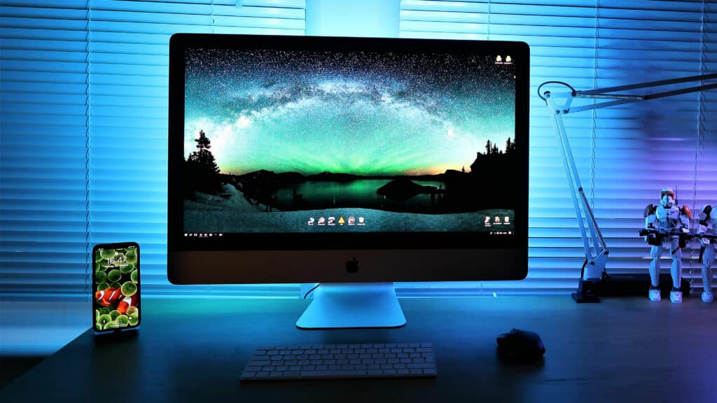 Kuva työpöydästä, jonka päällä oleva tietokoneen ja älylaitteen näyttö hohkaavat sinistä valoa.